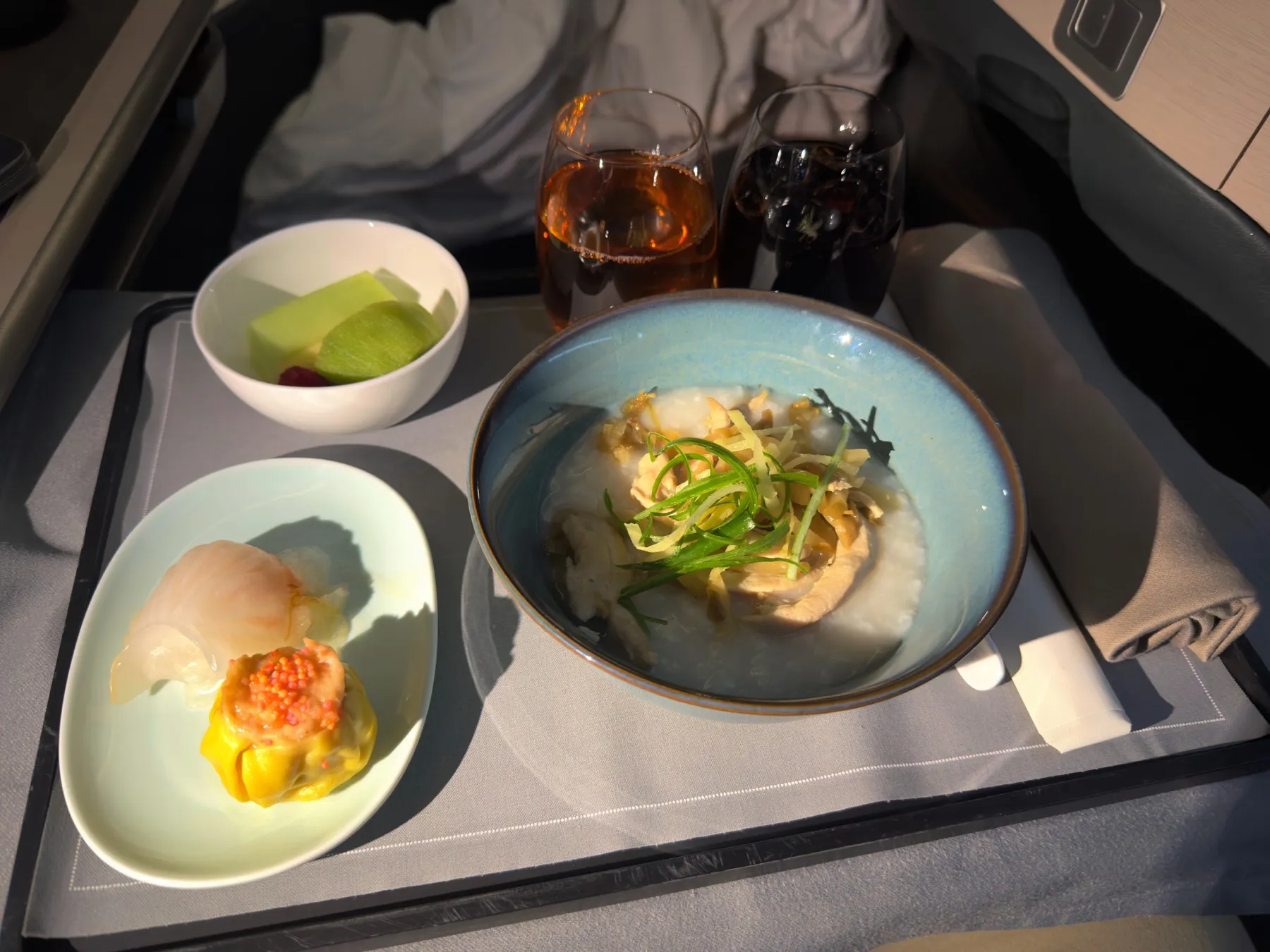 鸡肉粥配虾饺、烧卖和水果的港式早餐